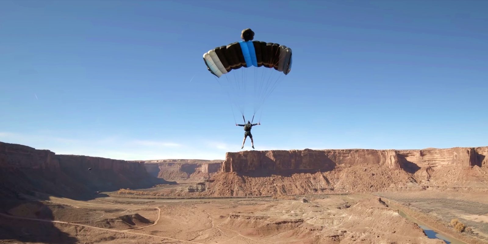 FPV drone flies in between parachute strings of BASE jumper